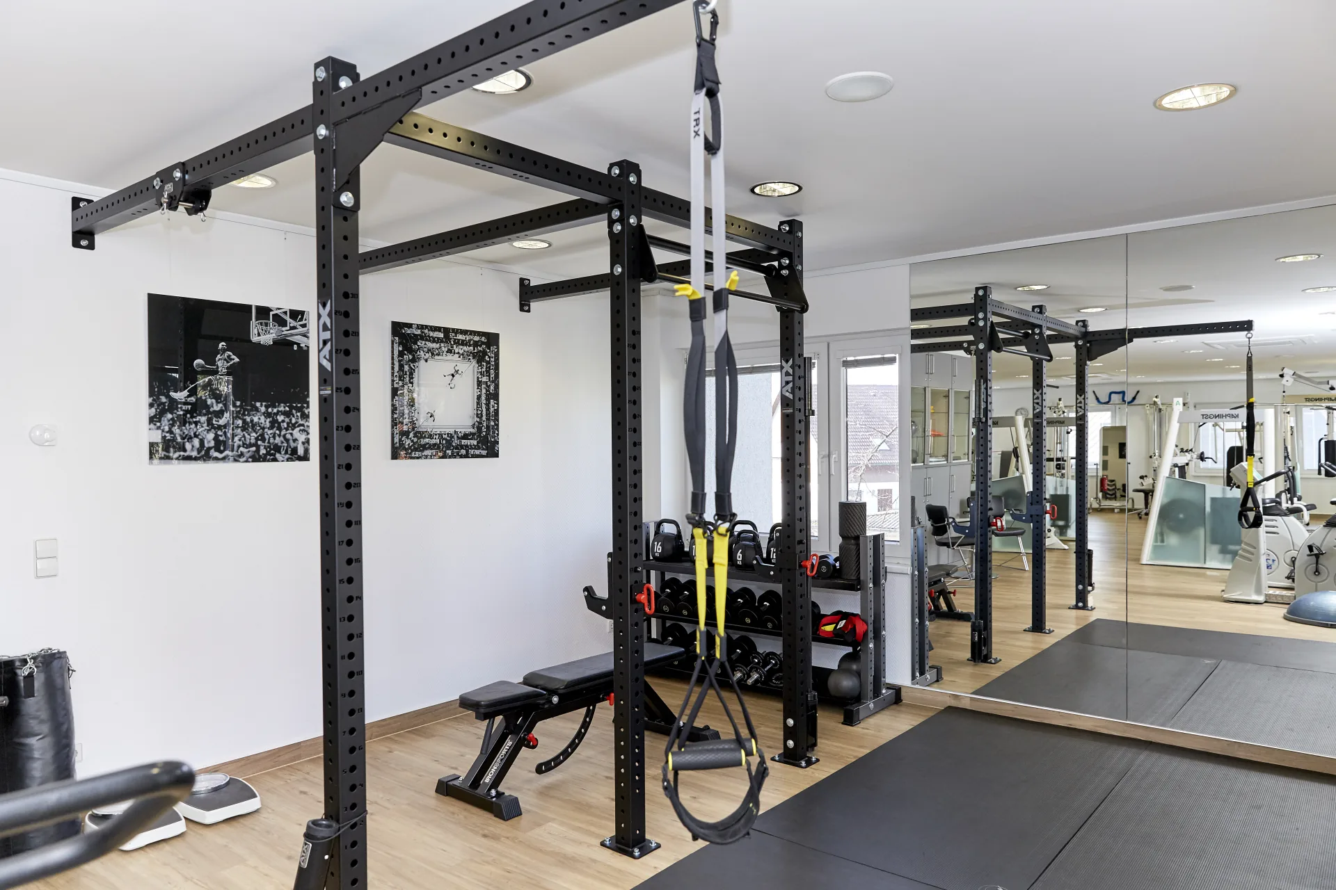 Hochwertiges ATX Functional Training Rack mit TRX-Schlingen und Kettlebell-Station vor einer großen Spiegelwand bei PHYSIOMED SÜD Berlin als moderner Arbeitsplatz für aktive Therapeuten.